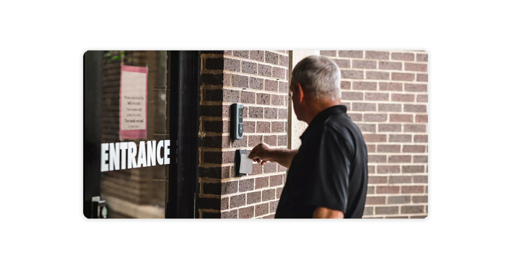 man using access control key fob on access control card reader terminal exterior building entrance